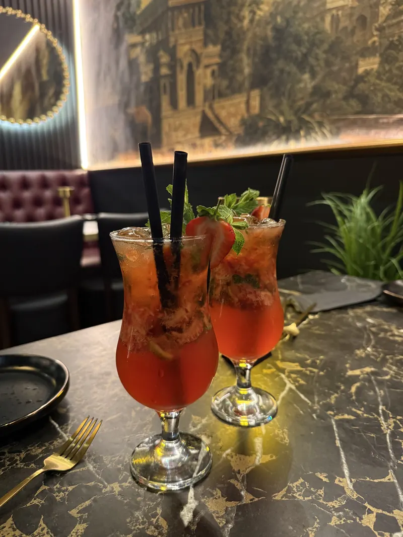 Two strawberry mojitos on a black-and-gold marble table at Indara