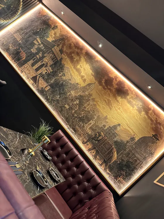 A backlit gold mural panel over a tufted booth